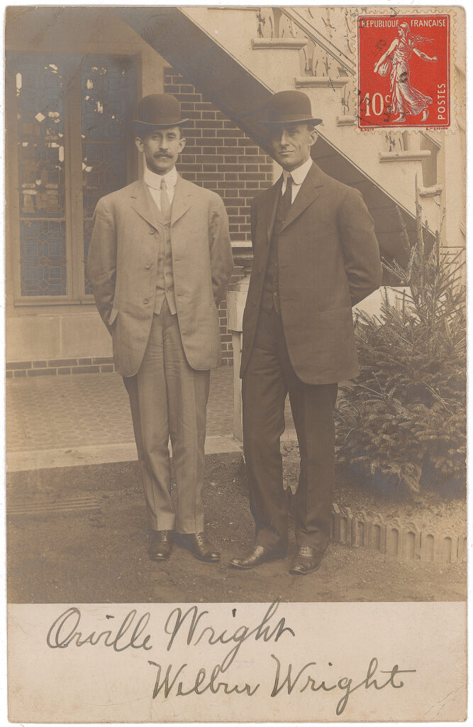 a postcard featuring a photo of a dapper Wilbur (right) and Orville (left) Wright that sold for $30,819. Their cursive signatures are visible at the bottom of the photo. 