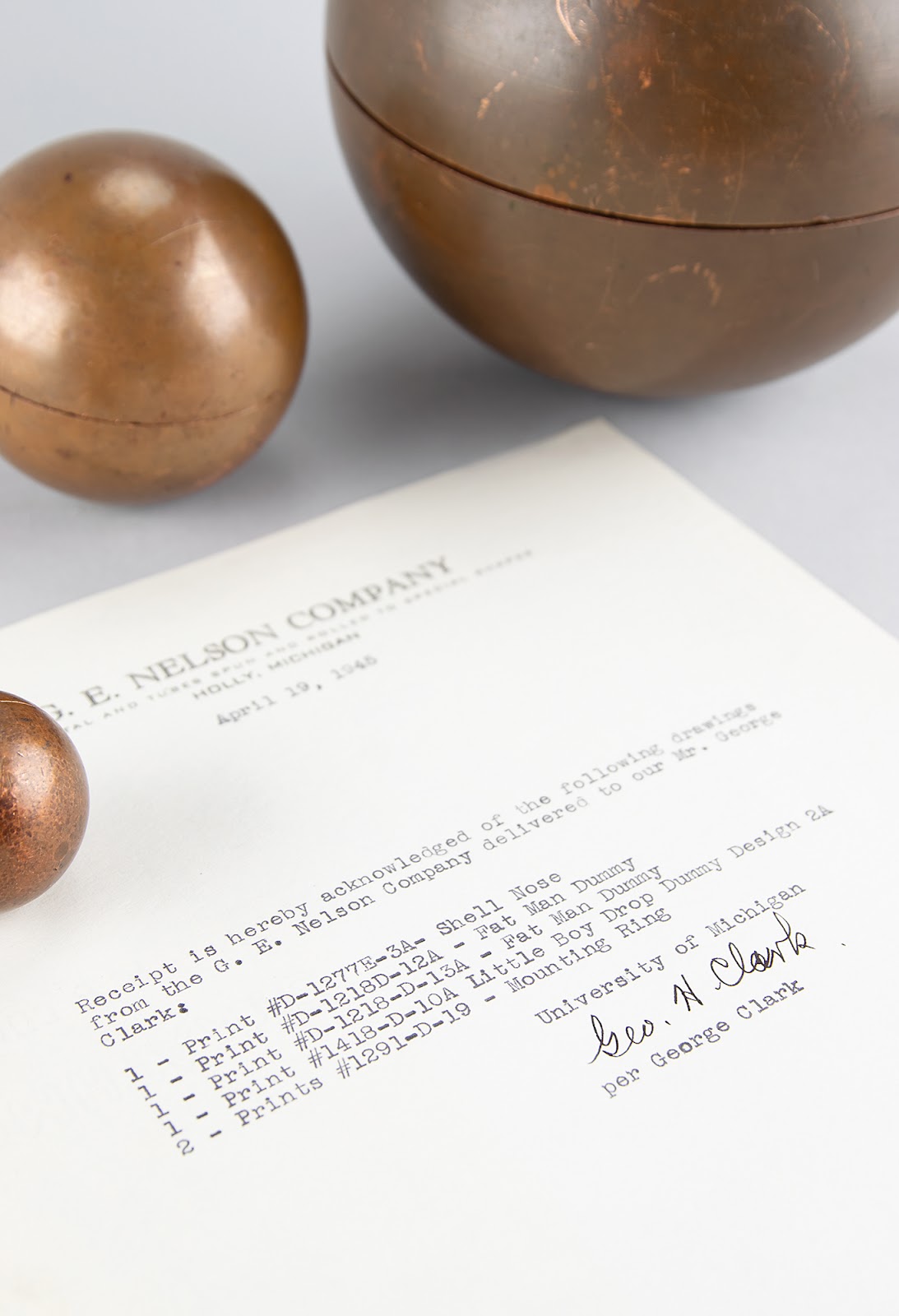 Three copper core spheres pictured with correspondence mentioning both atomic bombs from the Holly, Michigan-based G. E. Nelson Company.