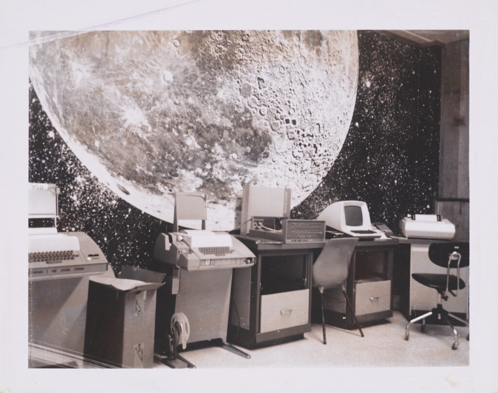 Byte Shop interior with early computers beneath a large lunar mural